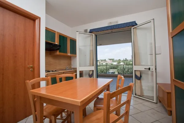Cucina e zona pranzo dell'appartamento con uscita su balcone