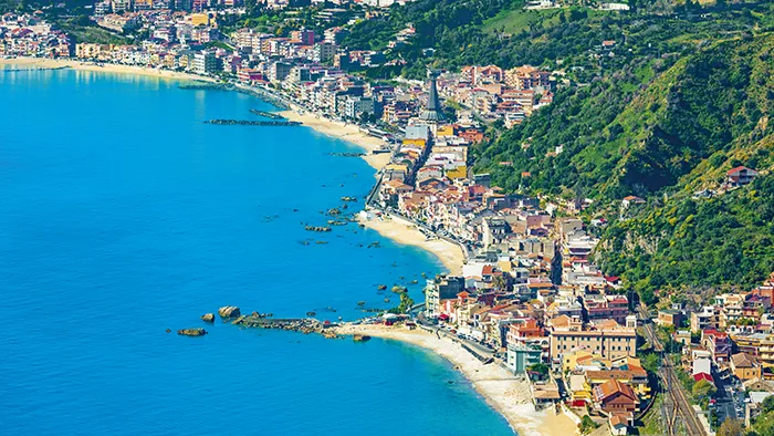 Panorama della costa siciliana con mare azzurro, spiaggia e paese ai piedi della collina