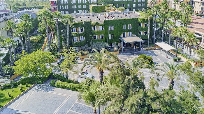 Veduta aerea dell'hotel immerso nel verde con palme e ampio piazzale d'ingresso