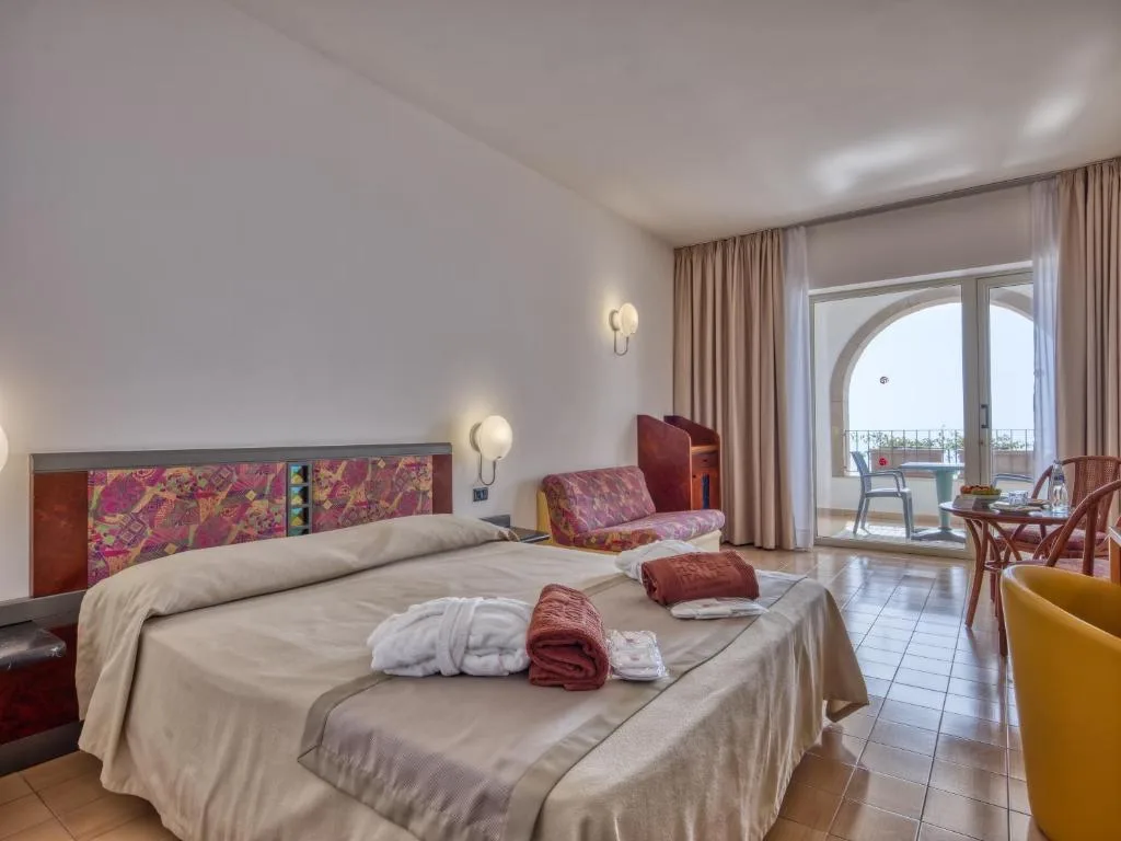 Camera da letto matrimoniale con balcone ad arco e accappatoi sul letto