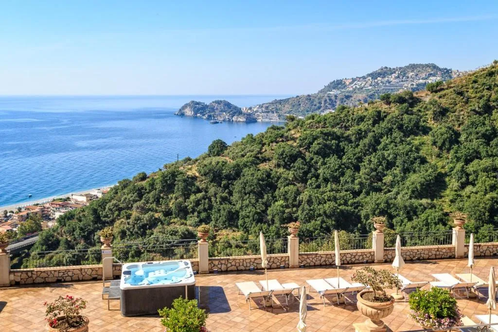 Terrazza con vasca idromassaggio e lettini affacciata sul mare e sulla baia