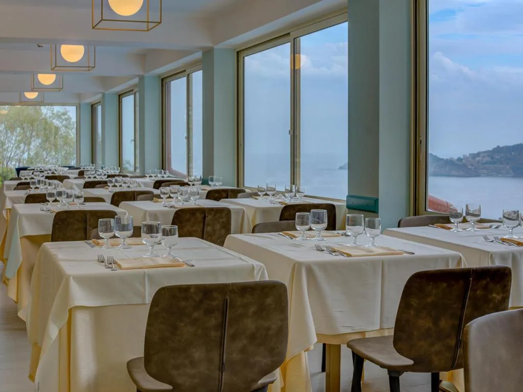 Sala ristorante elegante con tavoli apparecchiati e vetrate sul mare