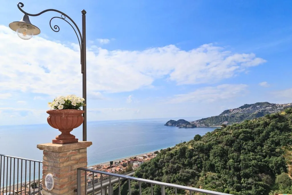 Balcone con lampione e vaso di fiori affacciato sul mare e sulla costa