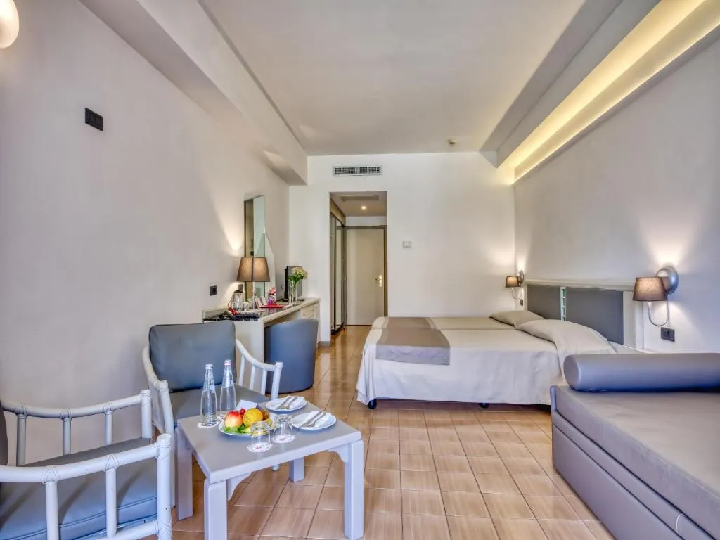 Camera moderna con letto, divano e tavolino con frutta e acqua