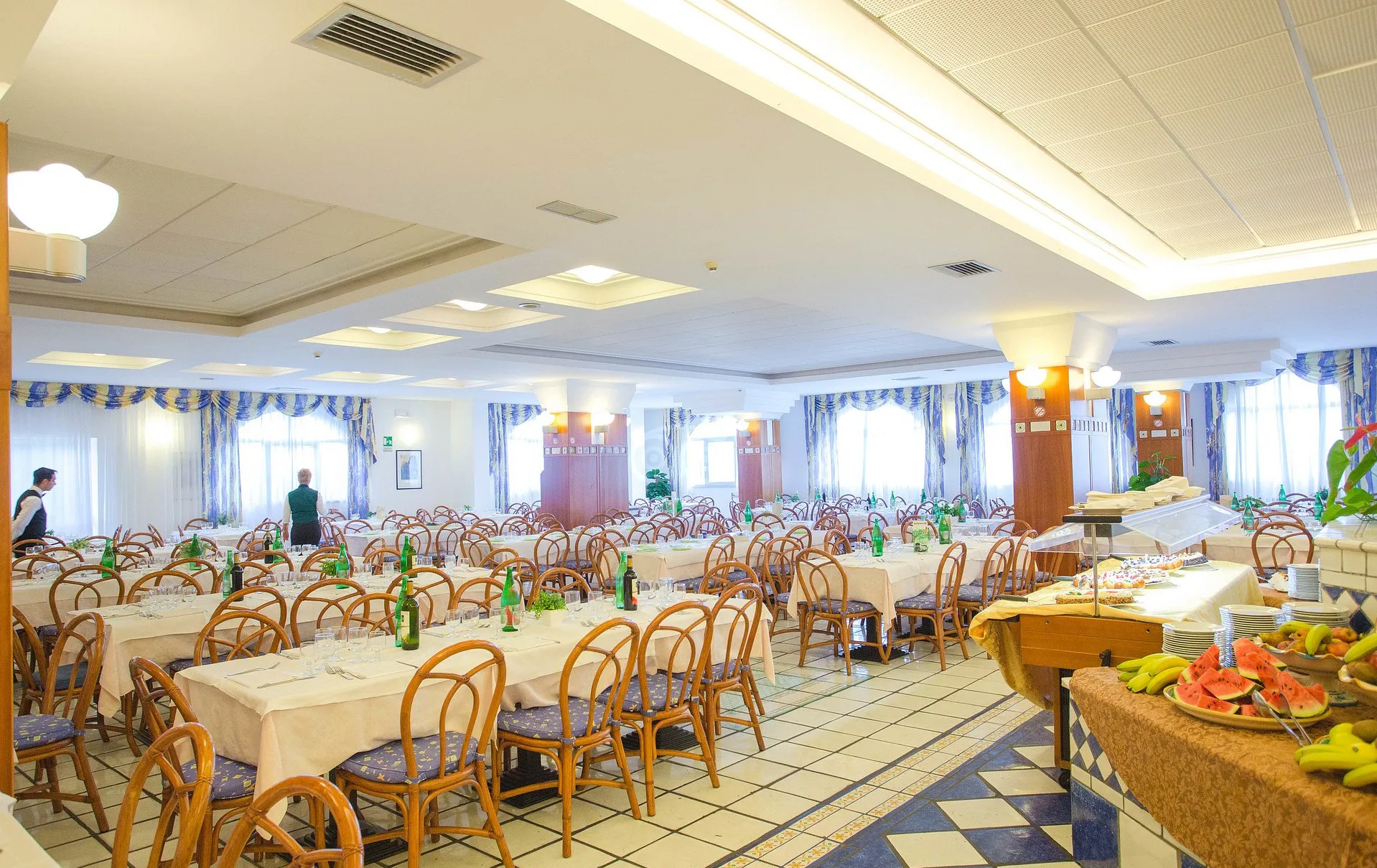 Sala da pranzo elegante con tavoli apparecchiati e buffet di frutta