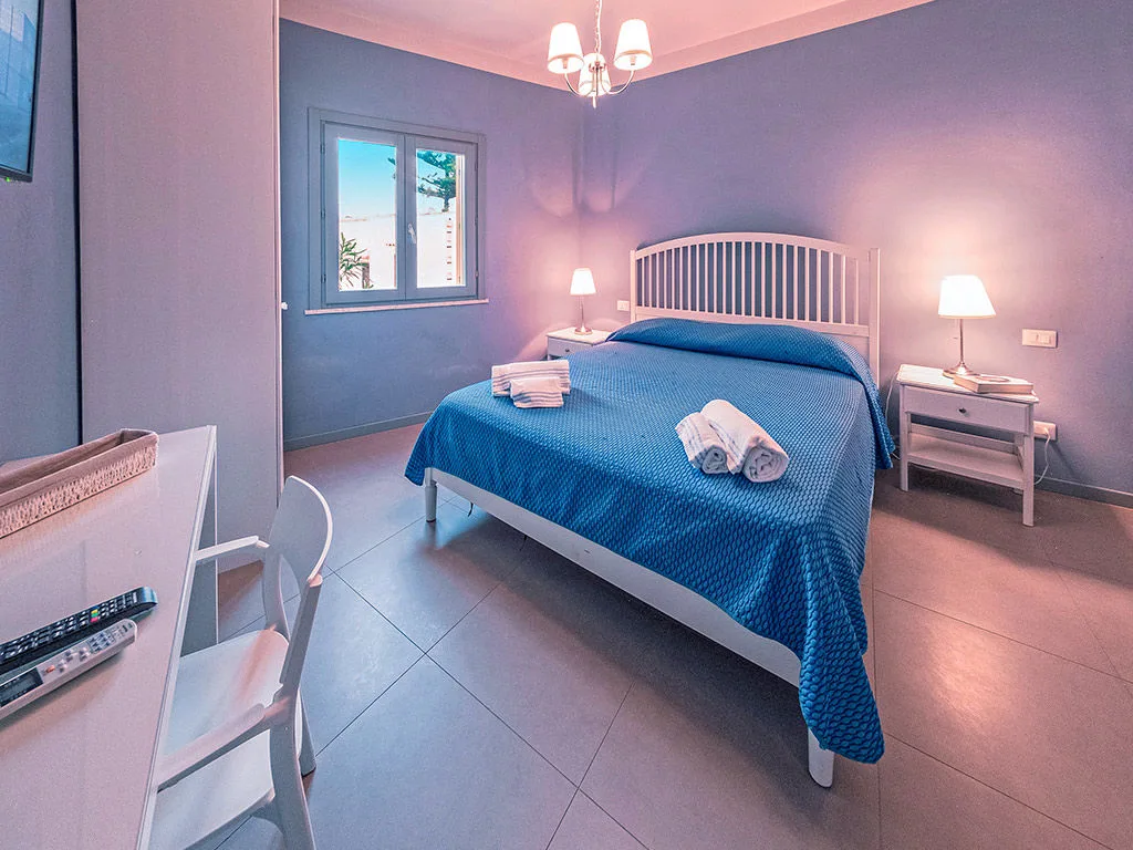Camera da letto con pareti azzurre, letto matrimoniale e scrivania
