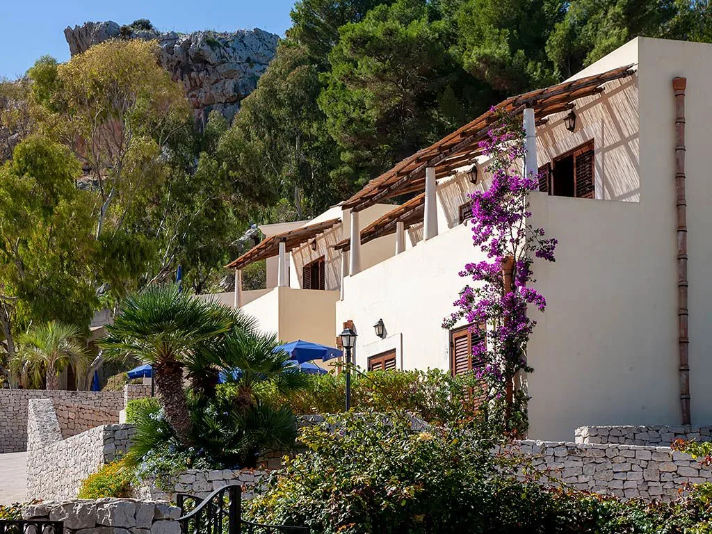 Edifici bianchi del resort con bouganville e montagna alle spalle