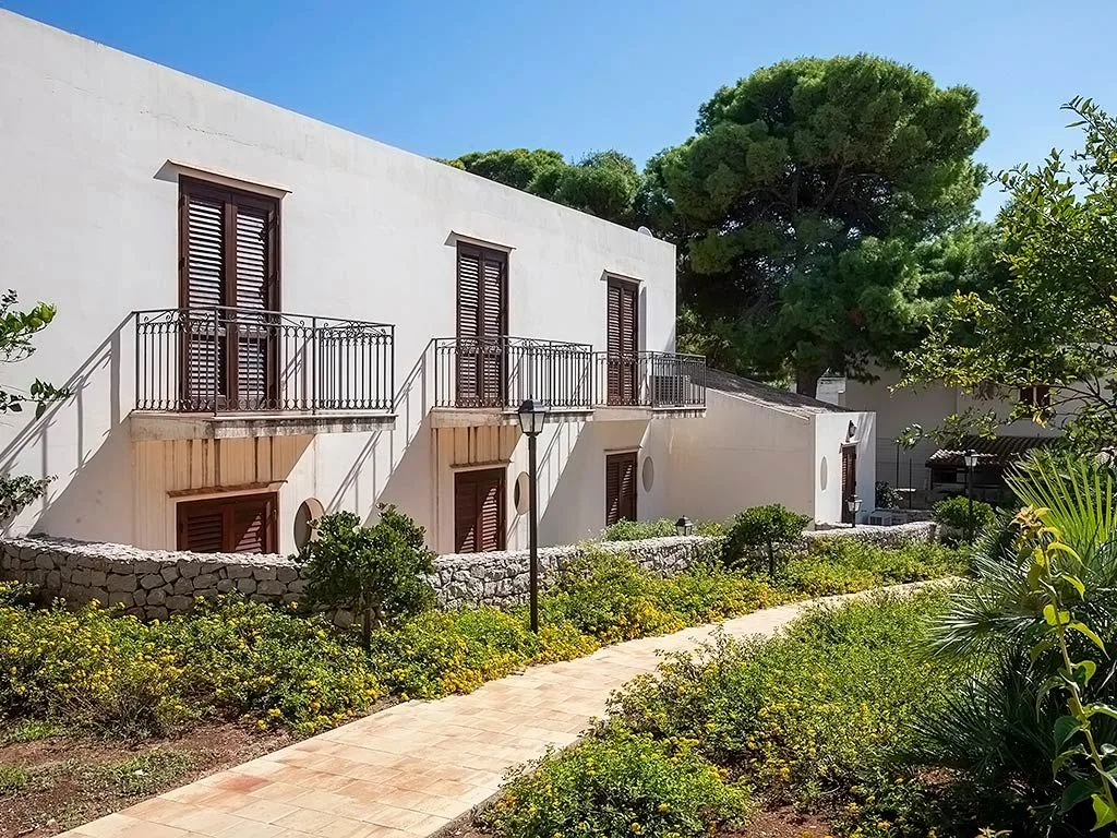 Facciata di edificio bianco con balconi e giardino curato
