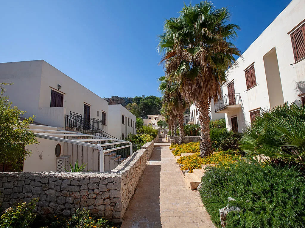 Vialetto tra gli edifici del resort con palme e vegetazione