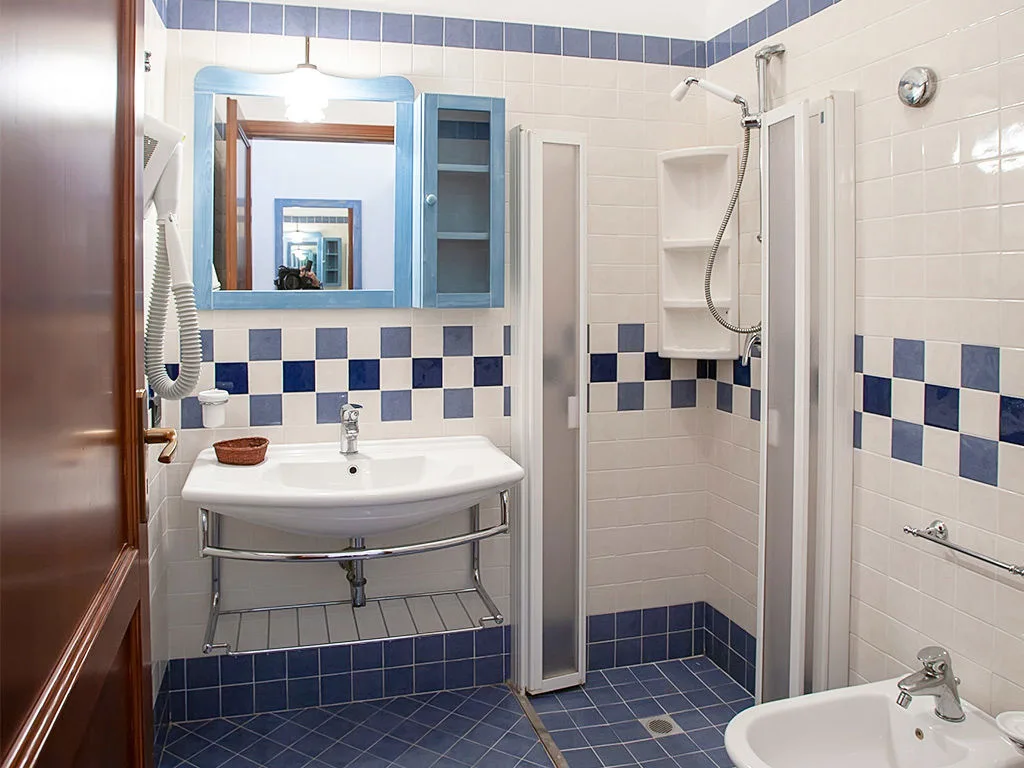 Bagno con piastrelle bianche e blu, lavabo, doccia e bidet