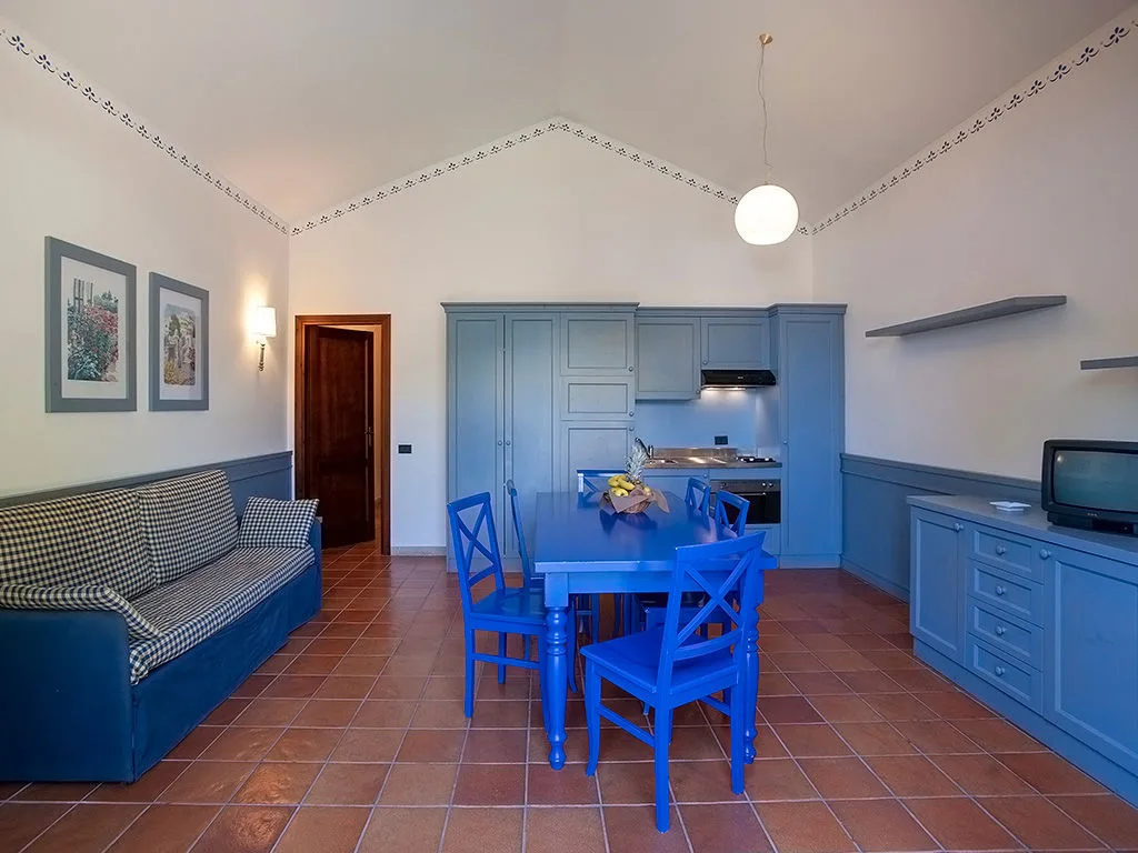 Soggiorno con cucina blu, tavolo da pranzo e divano