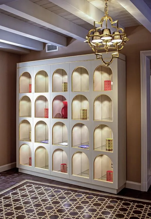 Mobile espositore bianco a nicchie ad arco con lampadario dorato e tappeto decorato