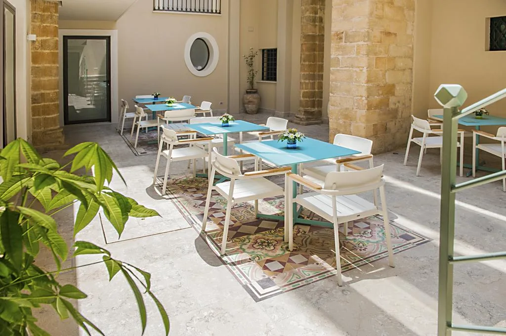 Area colazione nel cortile con tavoli azzurri, sedie bianche e pavimento a maioliche
