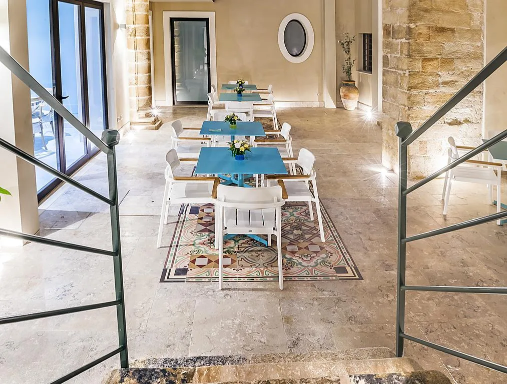 Area ristoro con tavoli azzurri allineati su pavimento in pietra e maioliche colorate