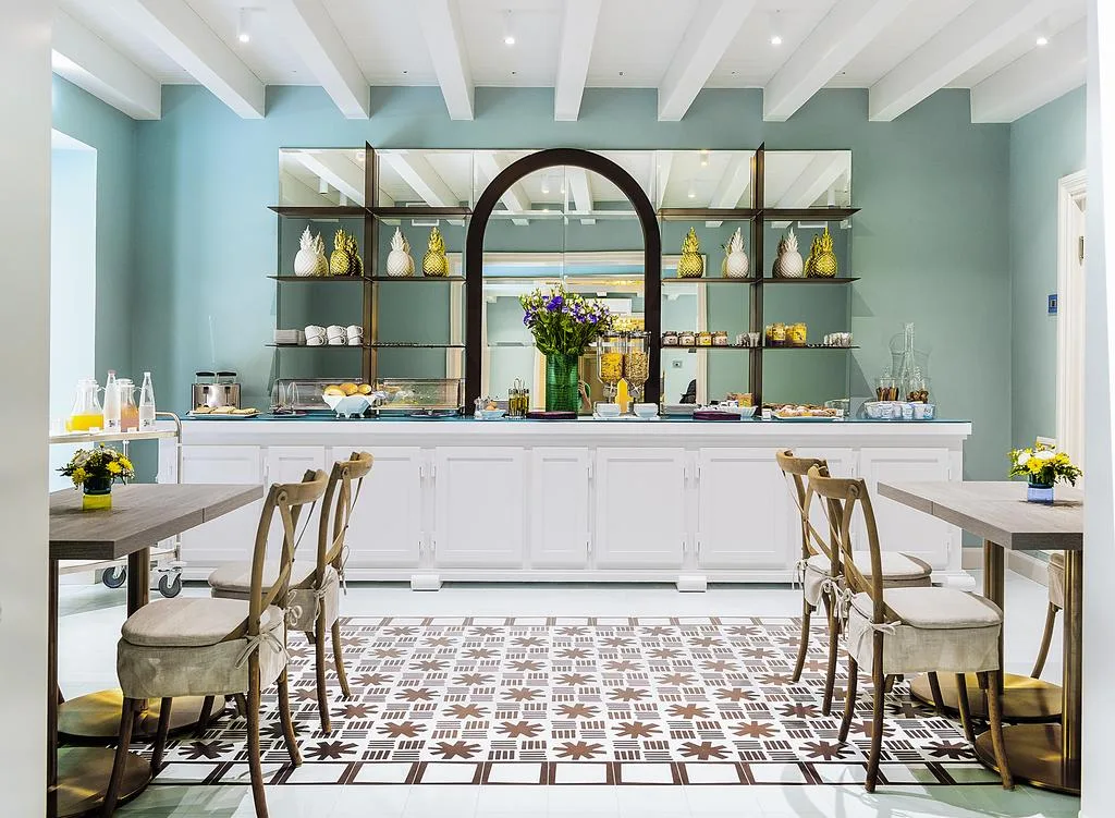 Sala colazione con buffet bianco, pareti verde acqua e pavimento decorato