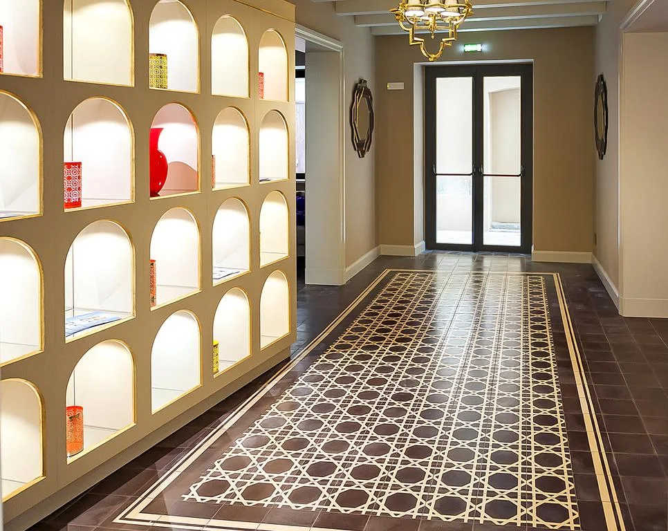 Corridoio con libreria a nicchie ad arco illuminate e pavimento decorato geometrico