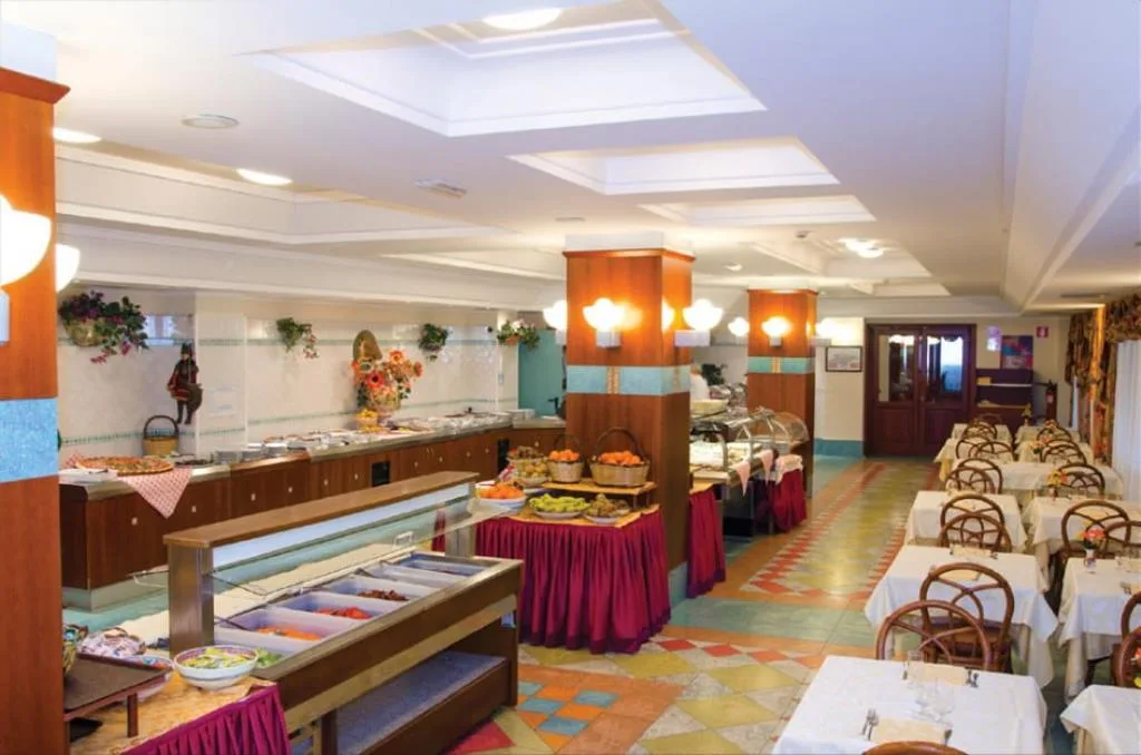 Sala ristorante con buffet allestito e tavoli apparecchiati, pavimento in maioliche colorate