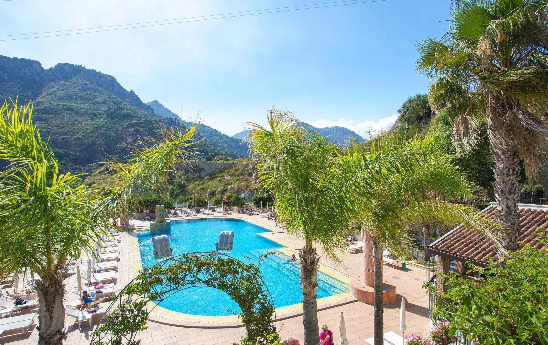 Piscina dell'hotel circondata da palme con vista sulle montagne