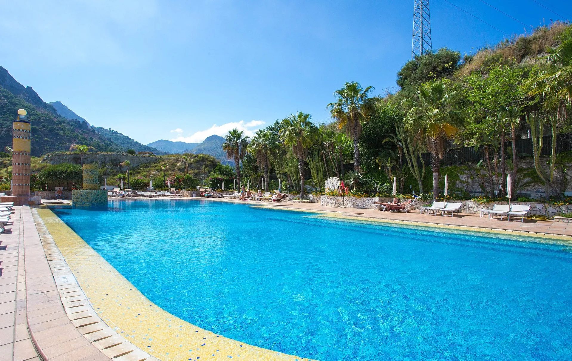 Ampia piscina esterna con lettini e vegetazione tropicale