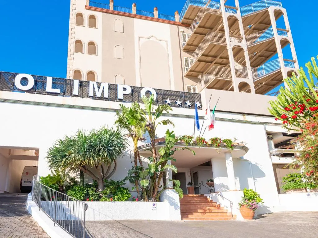 Ingresso dell'hotel Olimpo con piante e bandiere