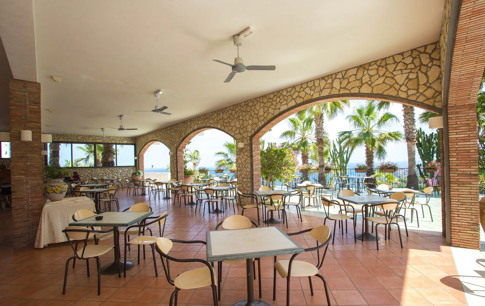 Sala ristorante con archi in pietra affacciata sul mare e sulle palme