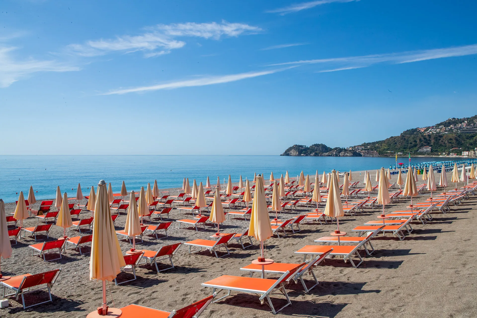 Spiaggia attrezzata con lettini arancioni e ombrelloni sul mare calmo