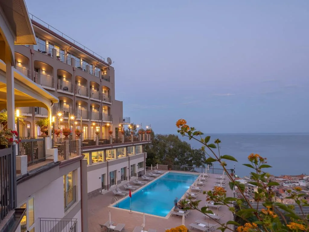 Hotel e piscina illuminati al tramonto con vista sul mare