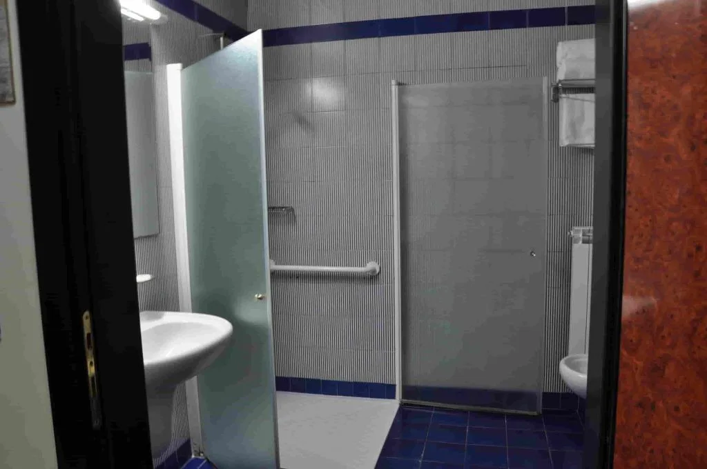 Bagno con doccia accessibile, maniglioni di sostegno e lavabo