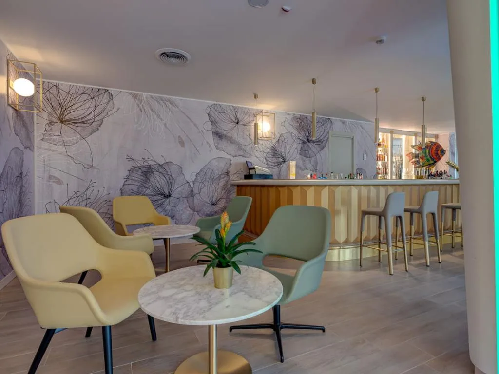 Bar lounge con bancone, poltrone colorate e decorazioni a parete