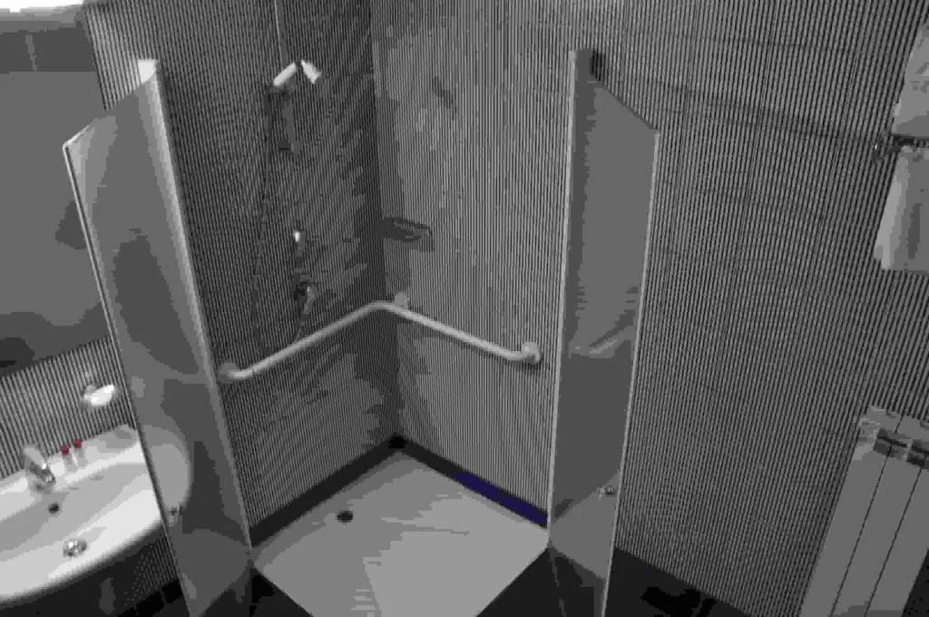 Bagno con doccia accessibile e maniglione di sostegno
