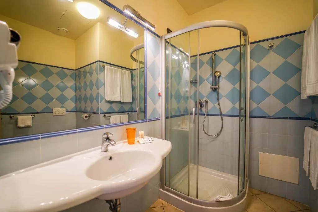 Bagno con piastrelle a rombi azzurri, lavabo e doccia con cabina in vetro
