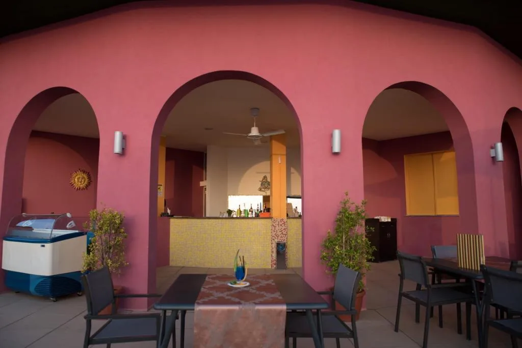 Bar esterno con archi rosa, tavoli, sedie e vetrina dei gelati