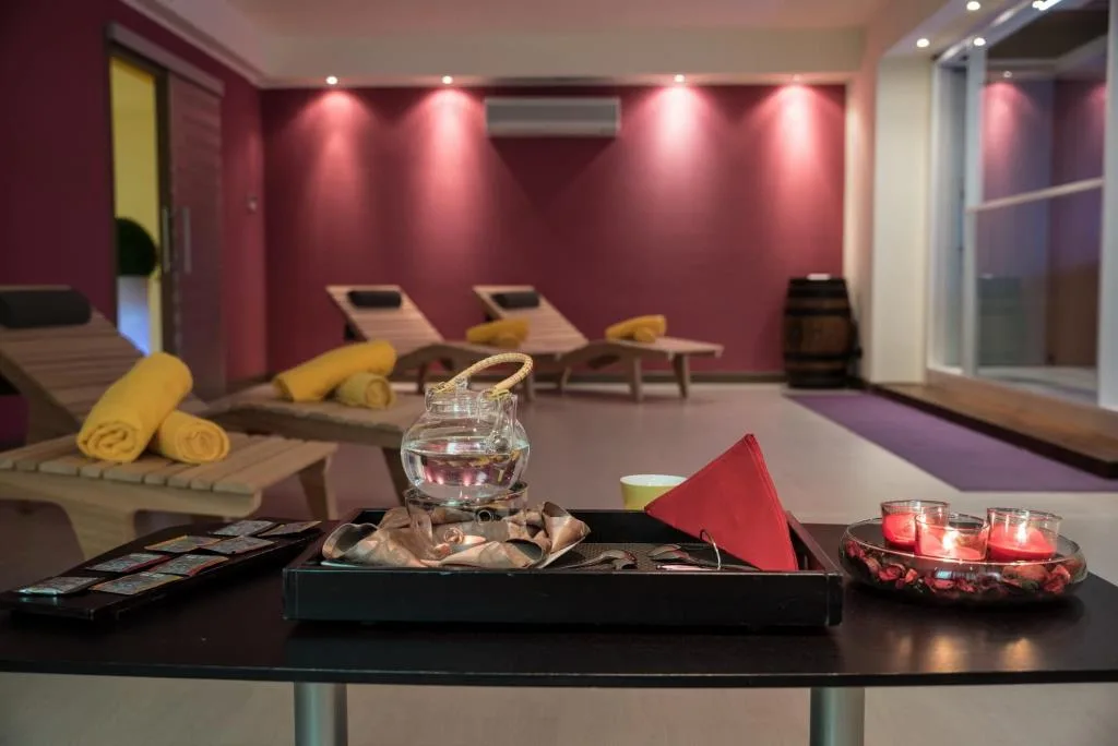 Area relax della spa con lettini in legno, asciugamani gialli e pareti bordeaux