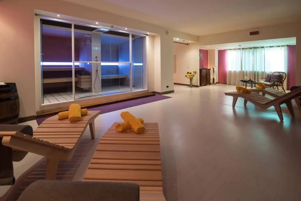 Zona benessere con sauna a vista, lettini in legno e asciugamani gialli