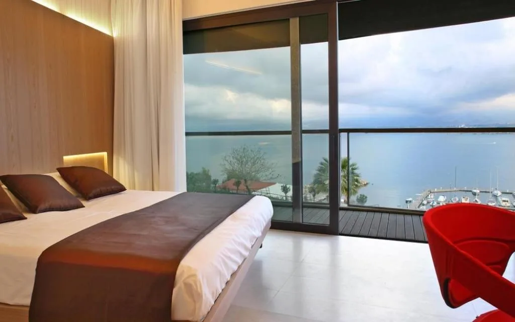 Camera contemporanea con grande vetrata e vista sul mare e sul porto turistico