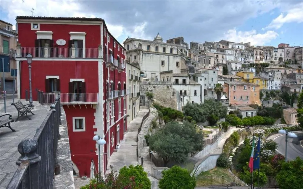 Vista esterna su edificio rosso e panorama del centro storico di Ragusa Ibla