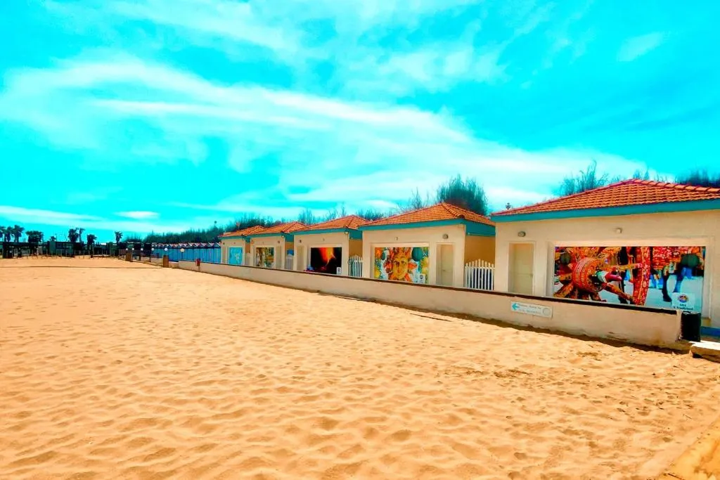 Cabine da spiaggia con murales colorati lungo la battigia sabbiosa
