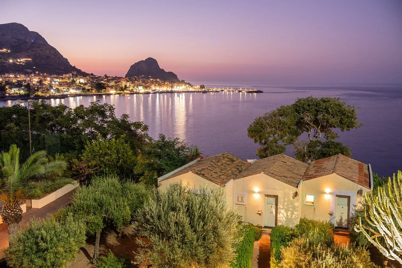 Cottage immersi nel verde con vista sul golfo e le luci della città al tramonto