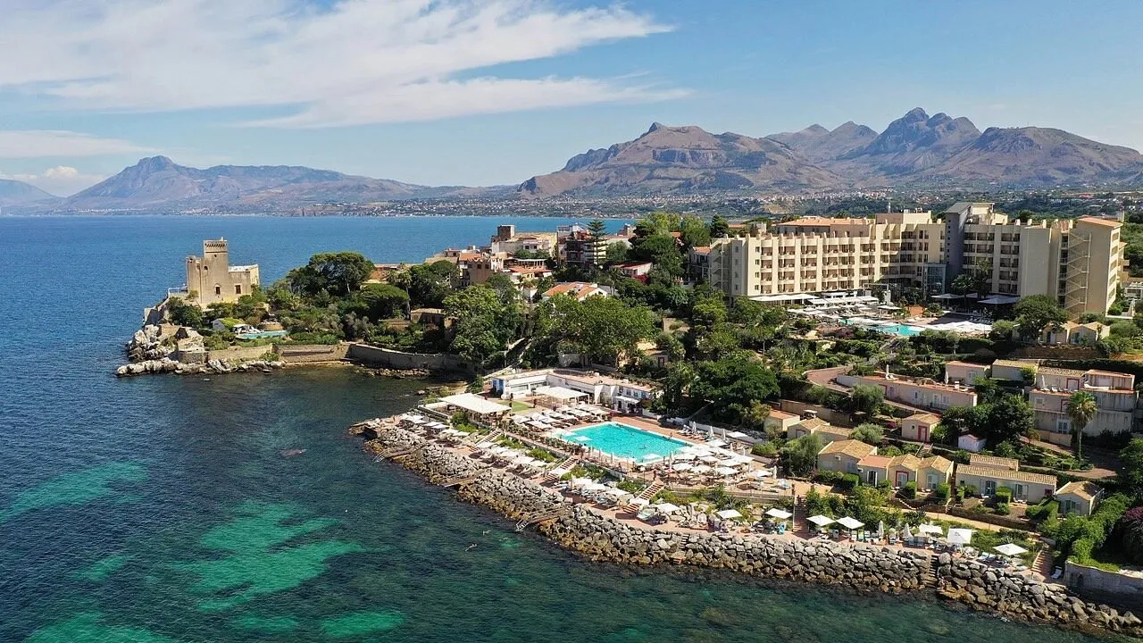 Panoramica del resort sulla costa con piscina, montagne e mare turchese