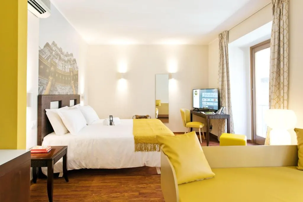 Ampia camera con letto matrimoniale, zona salotto gialla e scrivania