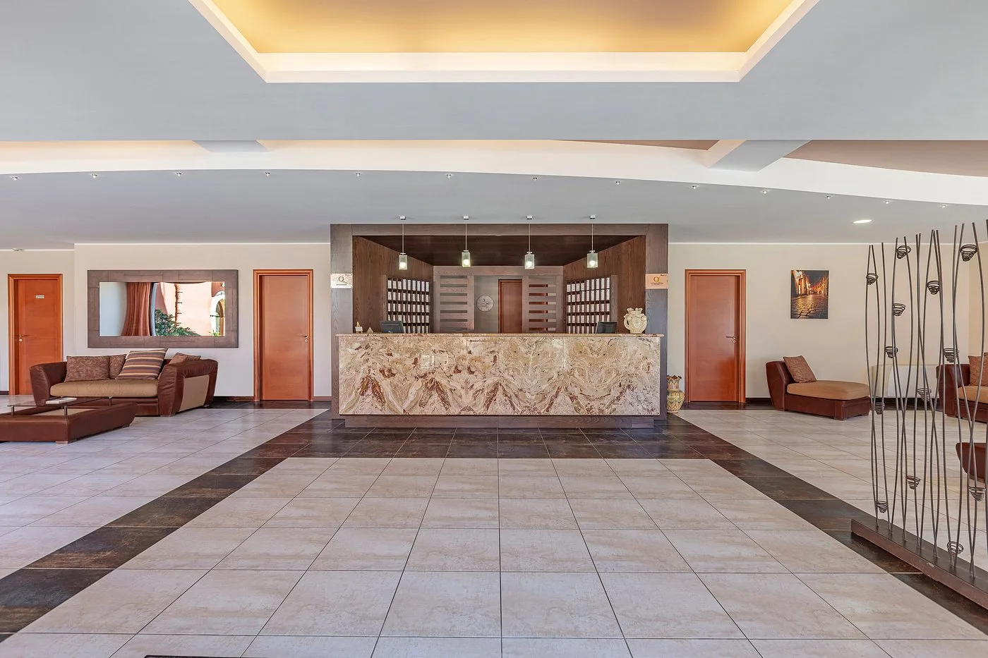 Reception dell'hotel con bancone in marmo, divani in pelle marrone e pavimento in piastrelle