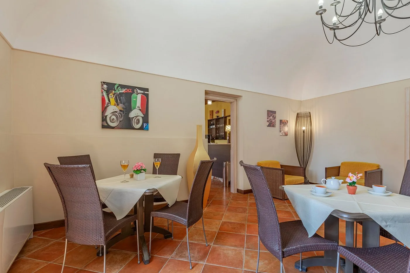 Sala colazione con tavoli apparecchiati, sedie in rattan e decorazioni alle pareti