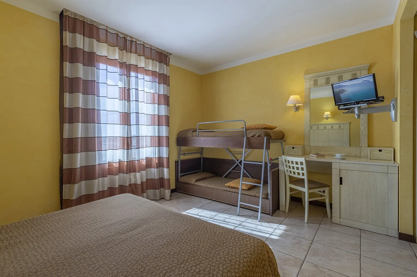 Camera con letto matrimoniale, letto a castello, scrivania e TV a parete