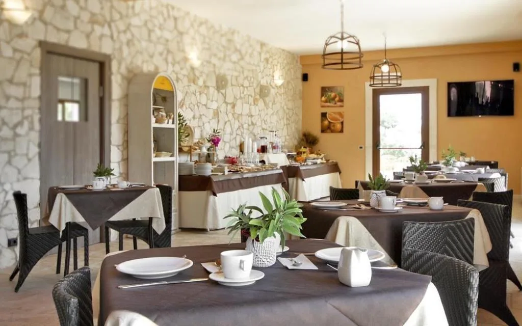 Sala colazione con tavoli apparecchiati e parete in pietra