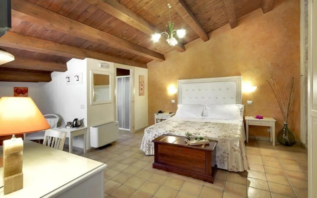 Camera spaziosa con soffitto in legno inclinato, letto matrimoniale e angolo scrivania