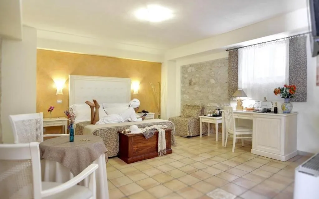 Ampia camera luminosa con letto matrimoniale, scrivania e parete in pietra