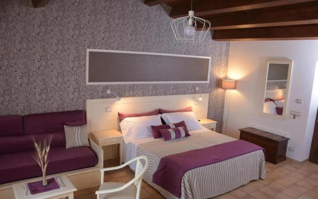 Camera elegante con divano viola, carta da parati floreale e letto matrimoniale