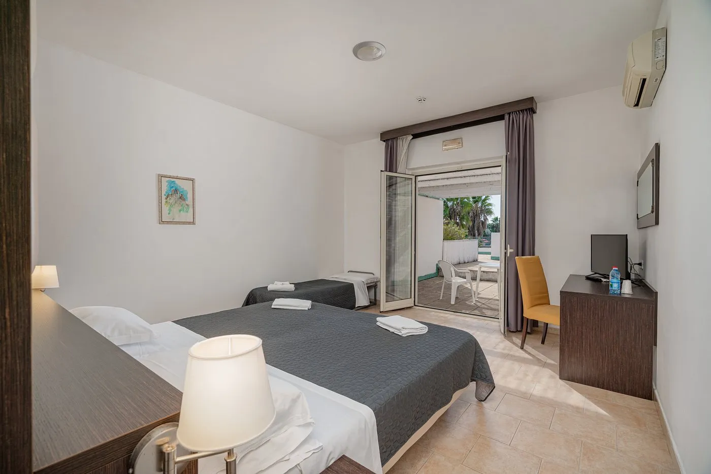 Camera con letto matrimoniale e singolo, TV e porta finestra sul terrazzo