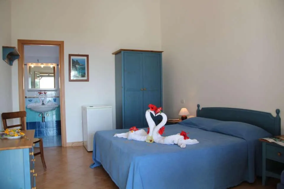 Camera matrimoniale con arredi blu, bagno e decorazione di asciugamani