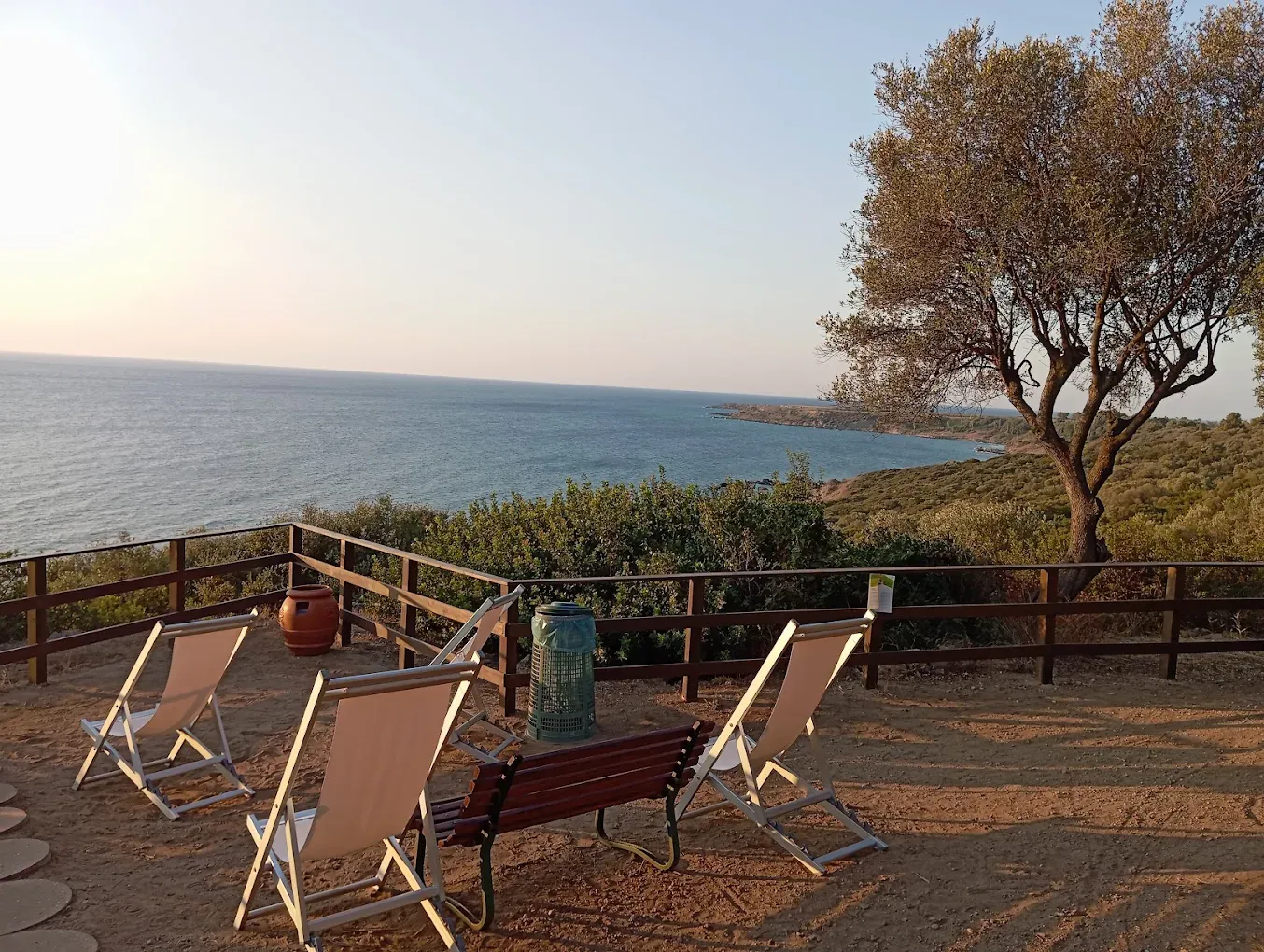 Terrazza panoramica al tramonto con sdraio e vista sulla costa e sul mare